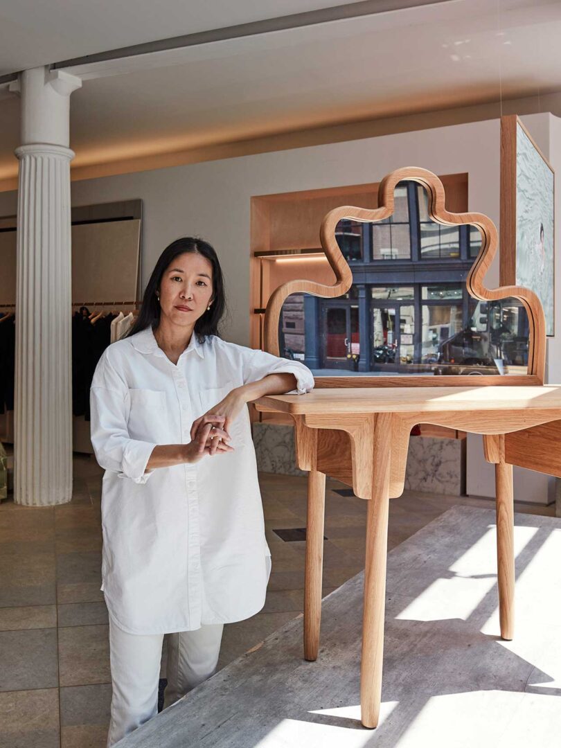 Asian woman standing next to wood table and mirror