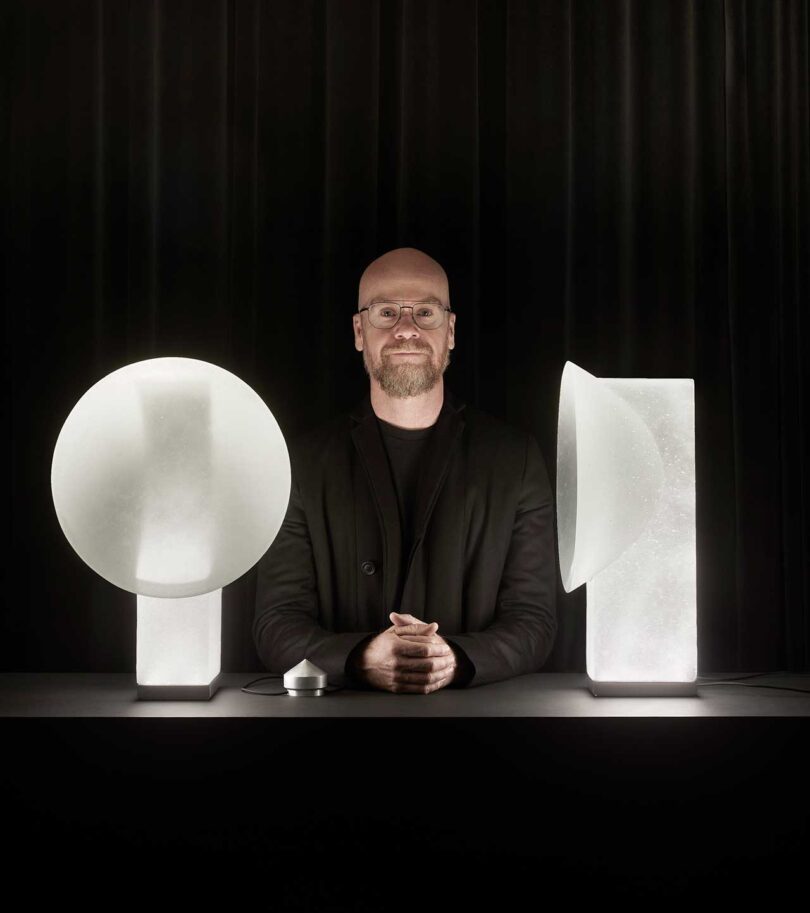 man standing between two frosted glass lamps in black