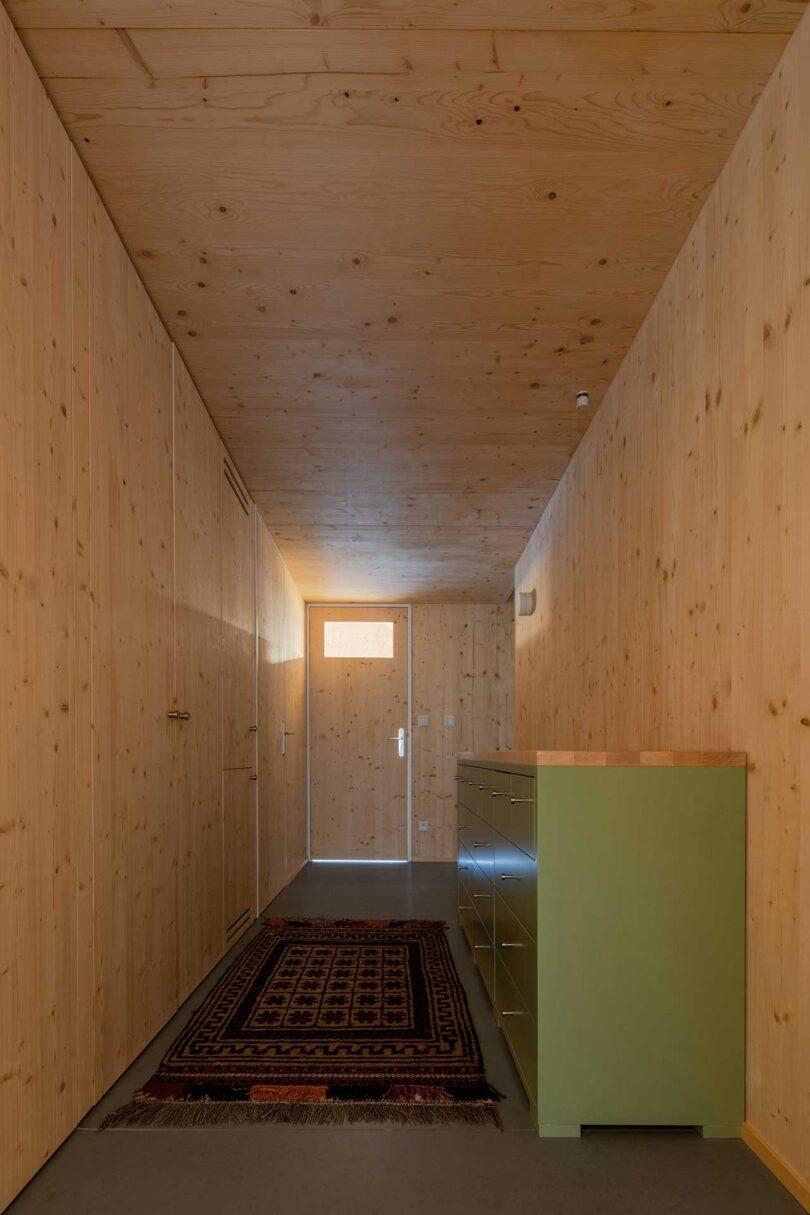 interior view of modern wood hallway with green dresser and door