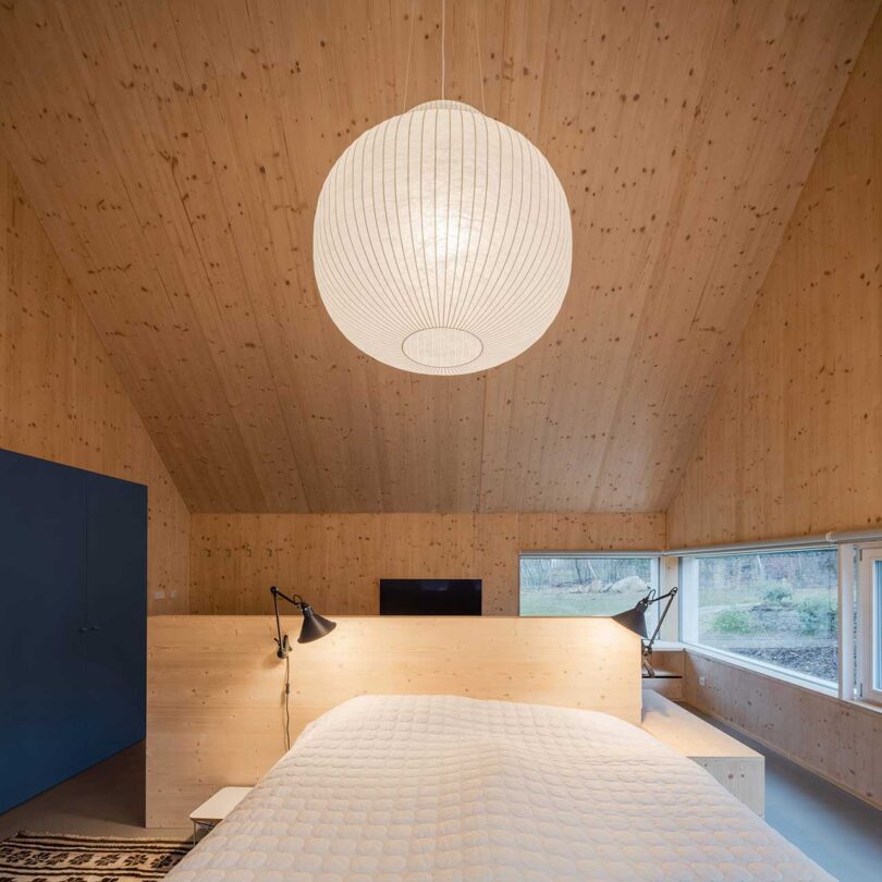 interior shot of room with pitched wood roof ceiling and bed