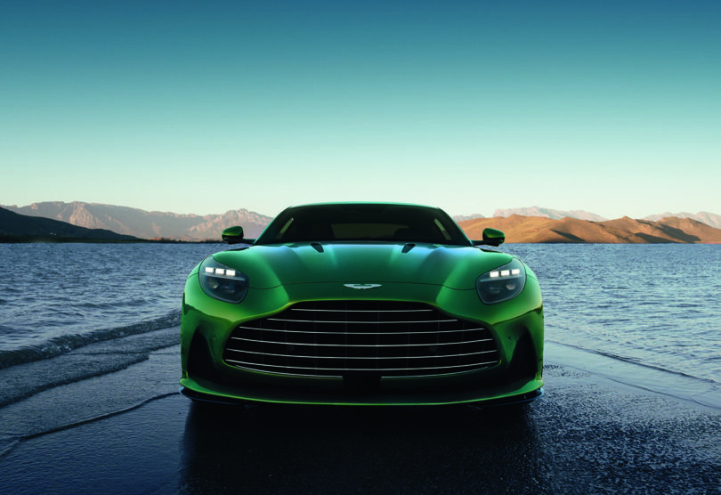Front view of Aston Martin DB12 in green parked on lake jetty.