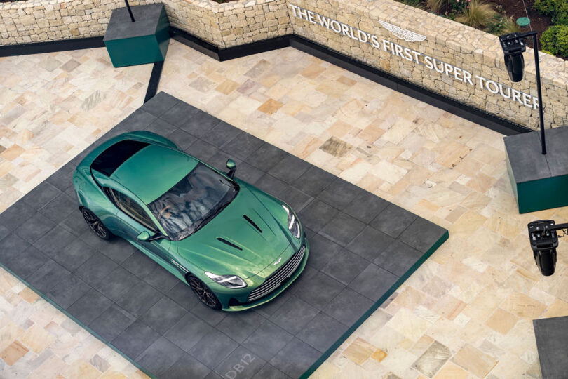 Overhead angled shot of parked Iridescent Green Aston Martin parked at Cote d'Azur hotel parking area.