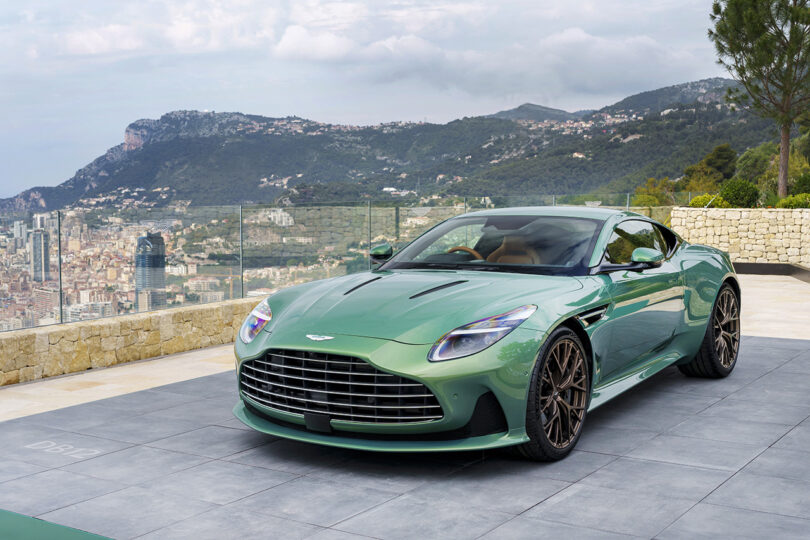 Front angled shot of parked Iridescent Green Aston Martin parked at Cote d'Azur hotel parking area overlooking Monaco.