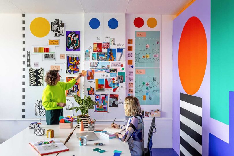 two women working in colorful office with small pieces of vibrant art on walls