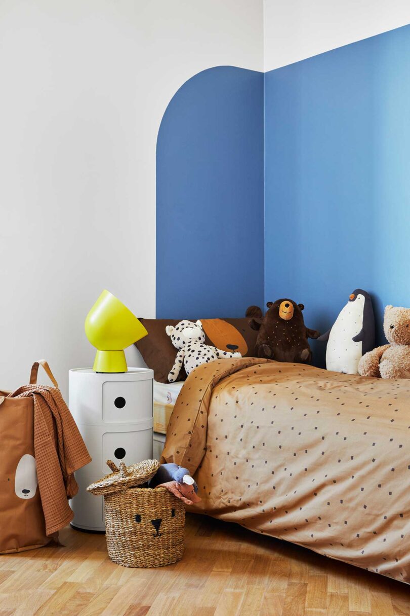 angled view of childrens bedroom with rounded blue mural on wall behind bed