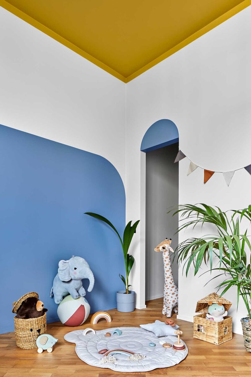 angled view of kids room with round blue shape on wall with stuff animals around