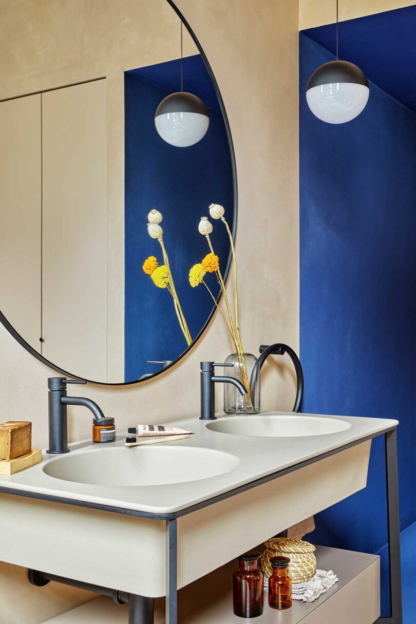 نمای زاویه‌دار حمام مدرن با سینک‌های دوتایی مدرن و دیوار آبی در پشت