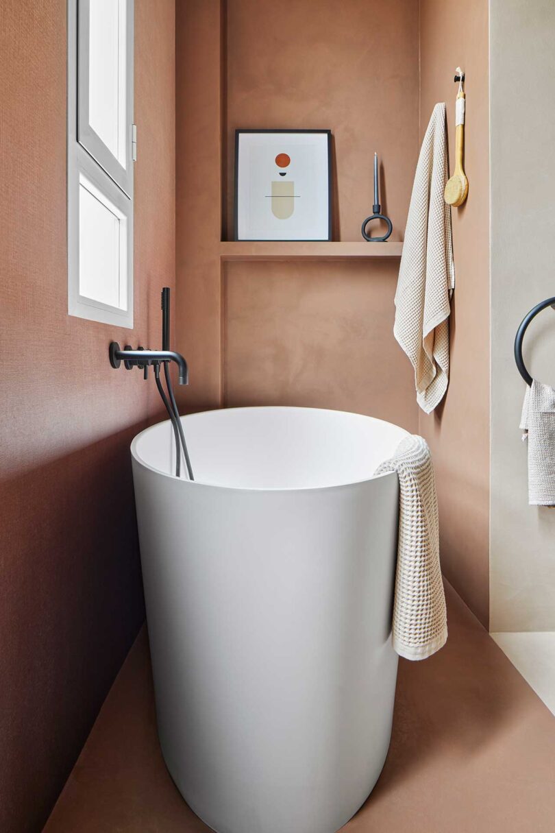 angled view in modern bathroom with pale pink walls and floating white tub