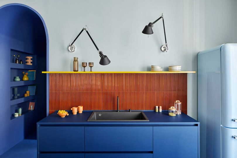 closeup of modern kitchen with vibrant blue lower cabinets and rust red tiles