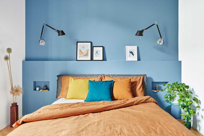 modern bedroom focused on bed with peach bedding and blue wall behind