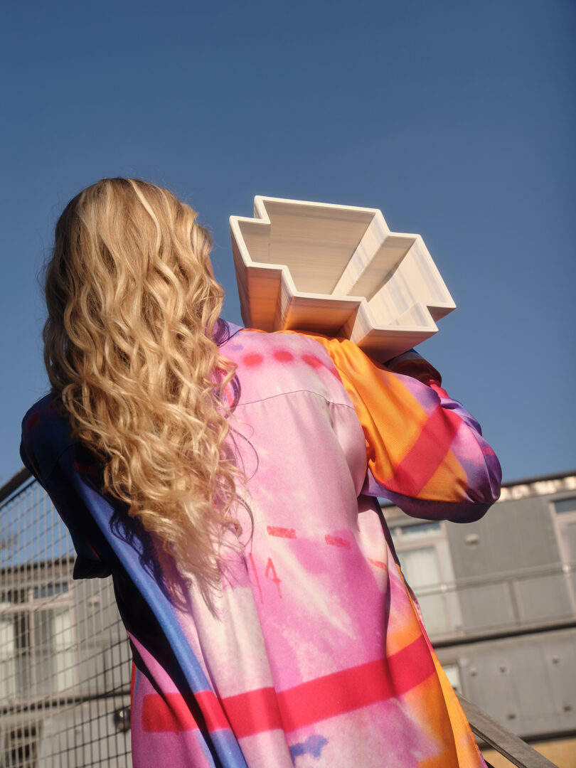 back of a person with long blonde hair holding a white bowl