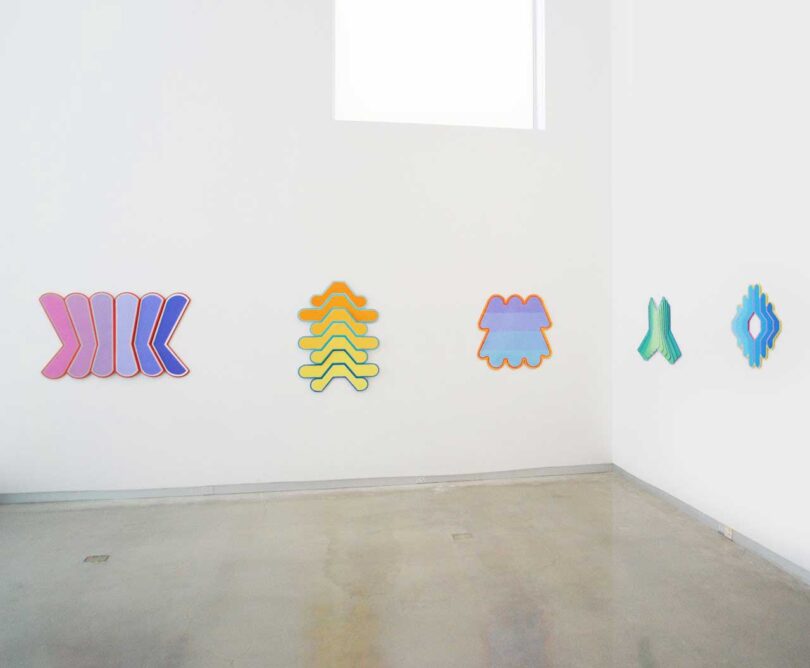 gallery interior with white walls and colorful abstract wall sculptures in gradient shades
