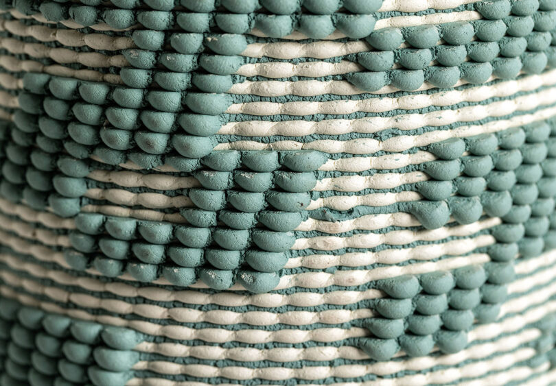Close-up of green and natural clay hued Dyadic Series dual extrusion 3D printed ceramic sculptures, showcasing their woven-like patterns and textures created by 3D printing with two clay colors simultaneously. 