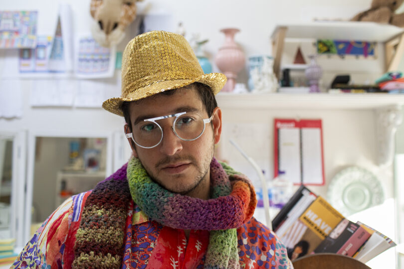 light-skinned person wearing glasses, a hat, and bright clothing