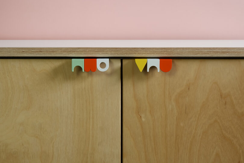 light wood cabinet doors with aqua, red, white, and yellow geometric hardware