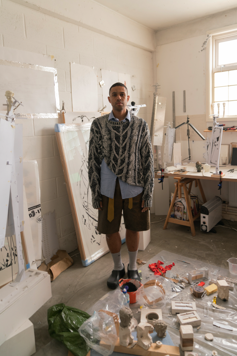 a man standing in the middle of a messy studio