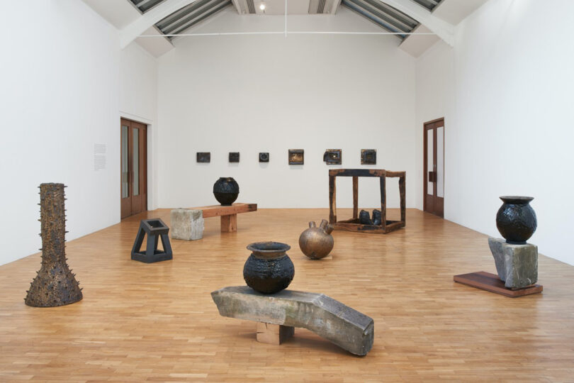 large gallery space with artworks on the wall and sculptures in the middle of the room