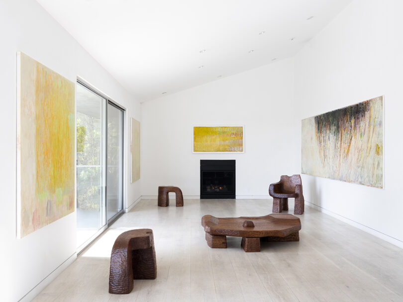 gallery space with large format art on the walls and abstract wood furniture