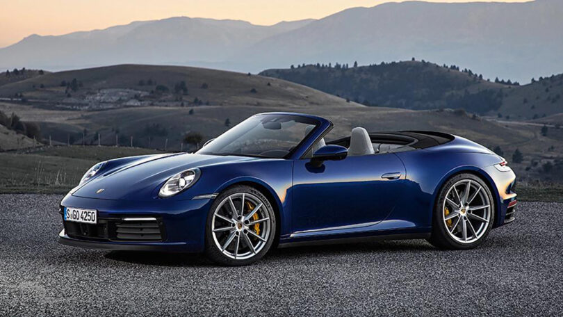 dark blue convertible sports car with a hilly landscape behind it