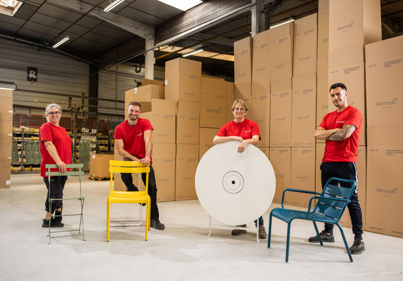 Four of Fermob's factory team in red t-shirts posing with Fermob outdoor furniture.