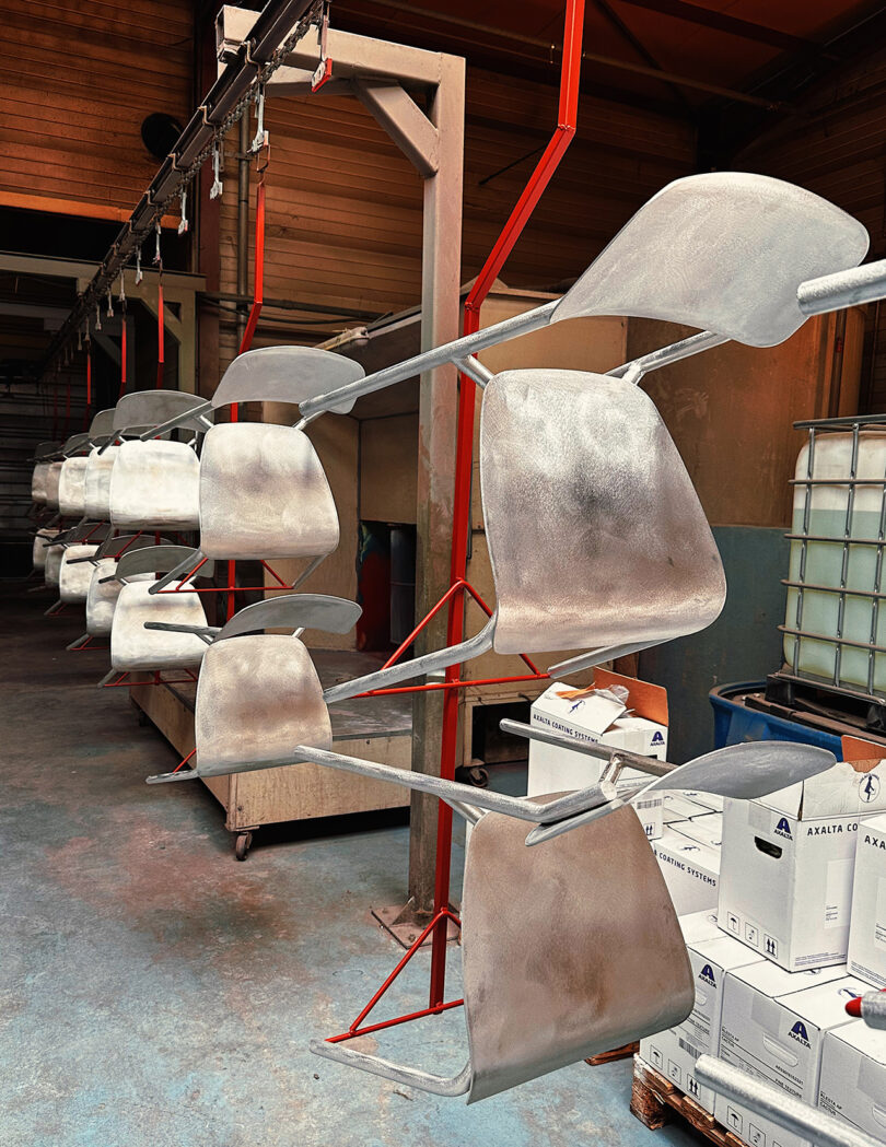 Assembly line of hanging unpainted Fermob Studie chairs waiting to be painted. 