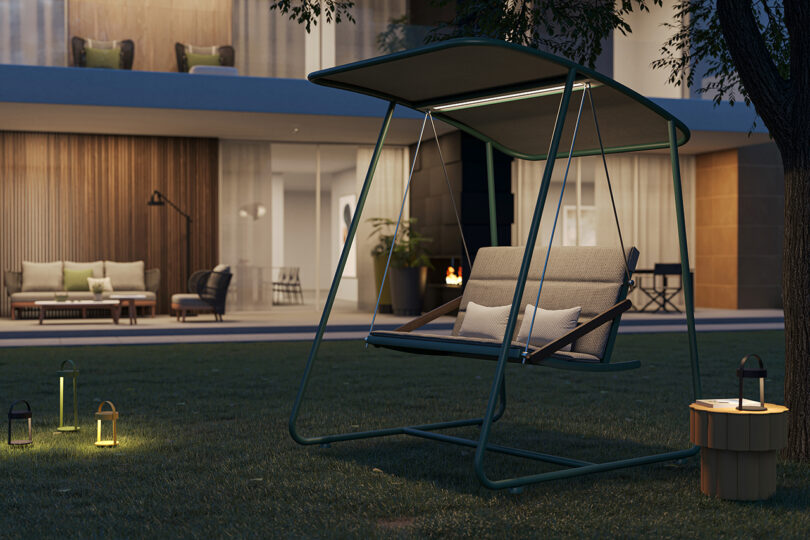 steel framed covered outdoor swing with cushion in a yard at night