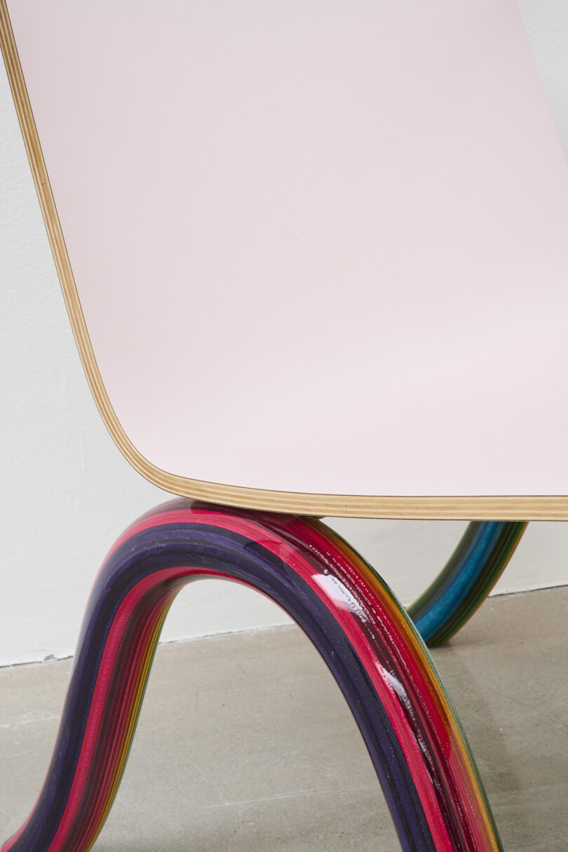 detail of lounge chair with rainbow plywood frame and pale pink seat