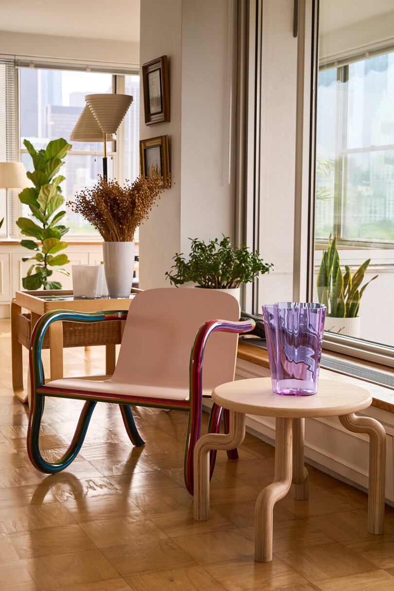lounge chair with rainbow plywood frame and pale pink seat in a styled living space