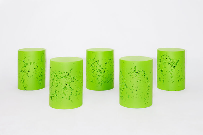 five neon green cylindrical stools on white background