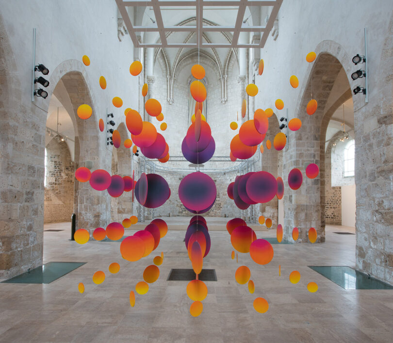 spacial sculpture in yellow, orange, purple, and red in a large open interior space