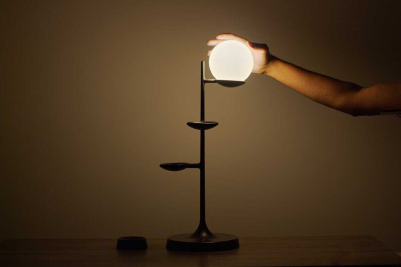 three tier lamp in dark space with hand touching globe
