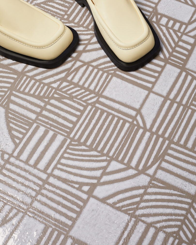 geometric white and beige tiled floor with a pair of white square-toed shoes