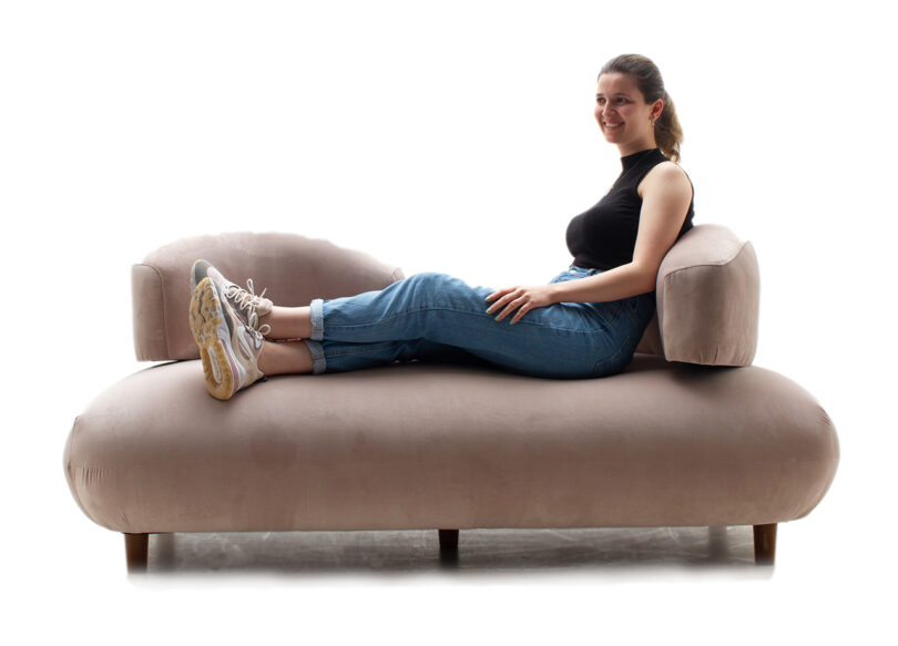 person sitting on light pink sofa with curved backrests