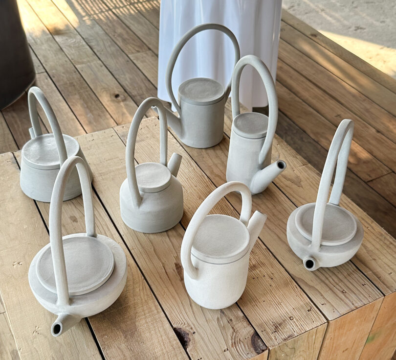 "Kind Void Gray" ceramic teapot collection by Lucila Rodarte, six shapes set upon wood pedestal.