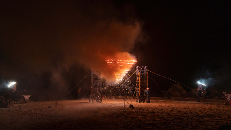 Pyramid shaped Mexican portable pyrotechnic frame structure set ablaze at night for firework show at Mexico Design Fair.