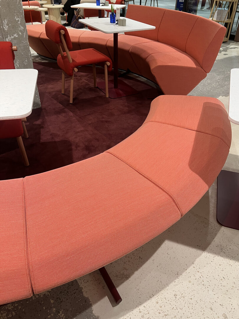light red/pink curved bench seating with red chairs and white tables