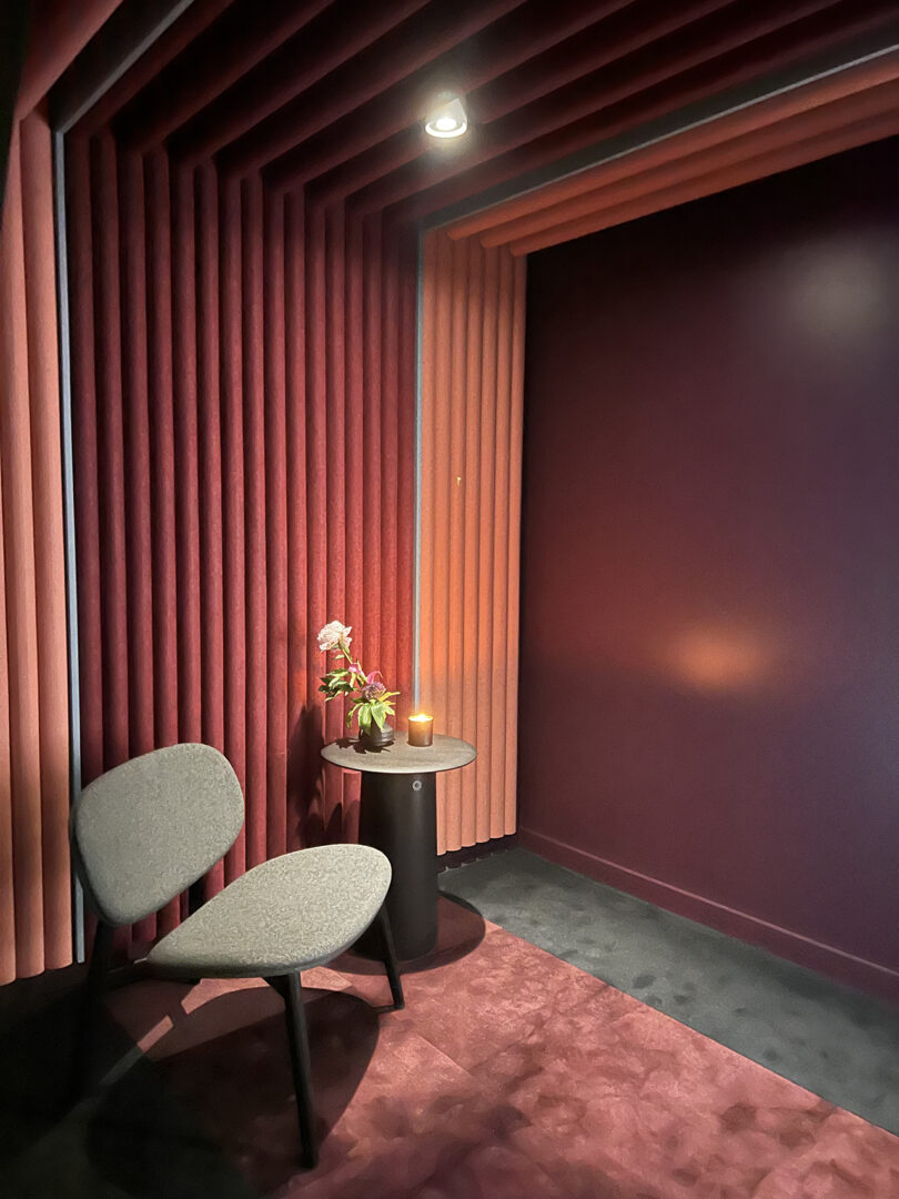 maroon and pink room with its wall and ceiling covered in tube-like acoustic material and a chair and side table