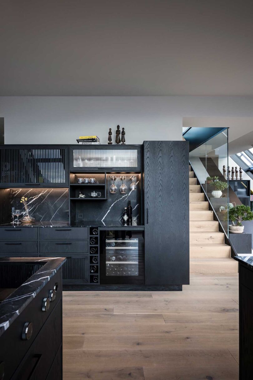 modern apartment interior black kitchen with wooden stairs to sid