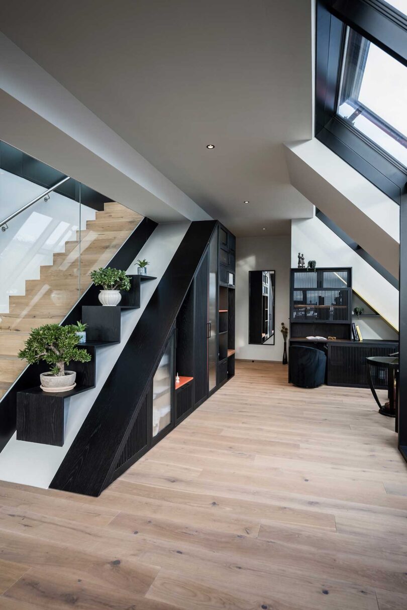 angled view of modern apartment interior with slanted black storage paired with staircase