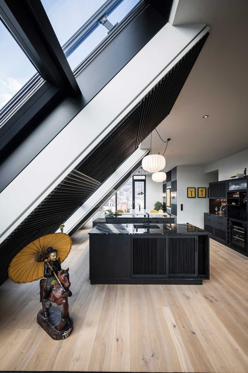 modern apartment interior with slanted glass walls with black kitchen in the middle