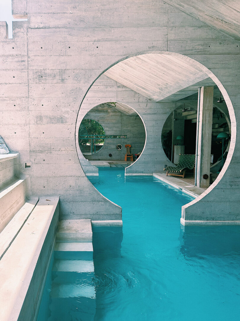View through circular concrete openings inside Casa TO hotel poolside lobby.