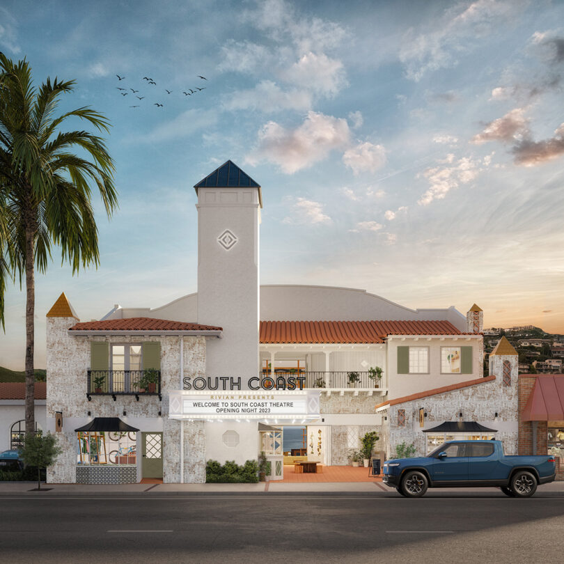 A converted movie theater in downtown Laguna Beach converted into the South Coast Rivian Spaces showroom with blue Rivian truck parked out front and sunset skies with clouds overhead.