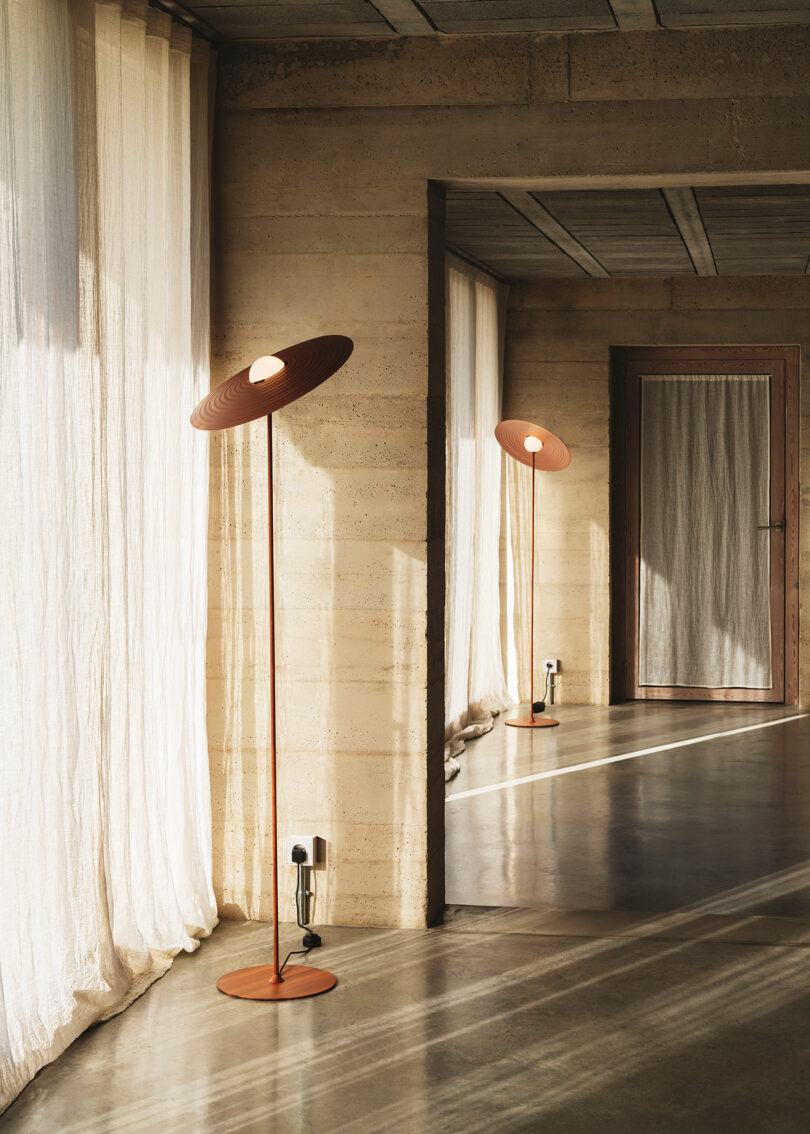 two burnt orange floor lamps with saucer-shaped shade in a living space