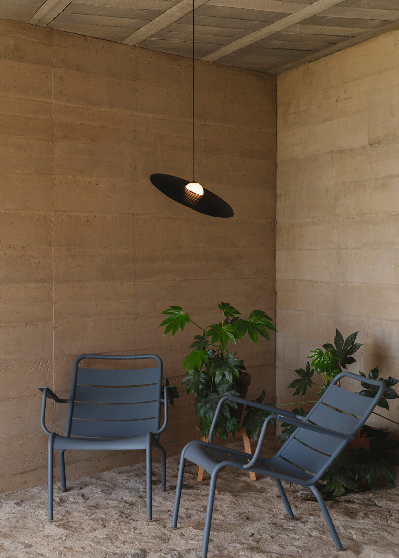 black saucer-shaped light pendants hanging over two outdoor chairs