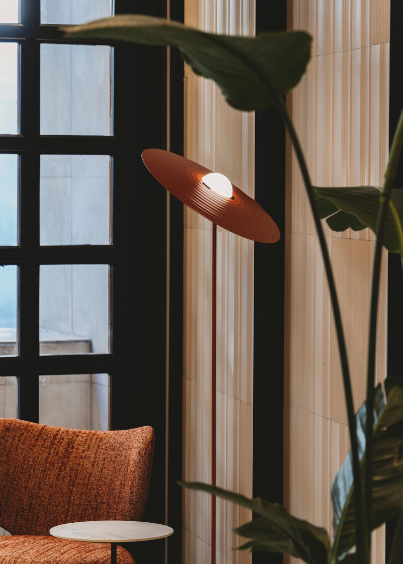 burnt orange floor lamp with saucer-shaped shade in a living space
