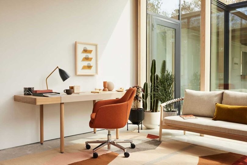 angled view of modern home office with minimalist desk with brown leather rolling chair