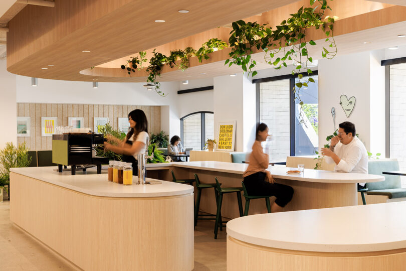 Tinder's coffee bar with barista preparing a shot with two employees seated at the bar laughing and woman in the background seated at a table work from her laptop.