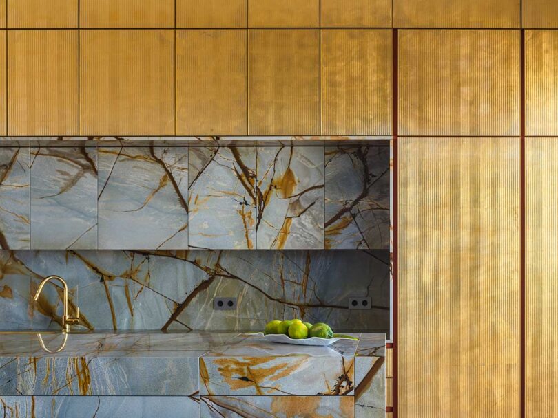 interior shot of modern kitchen with gold cabinets and marble backsplash