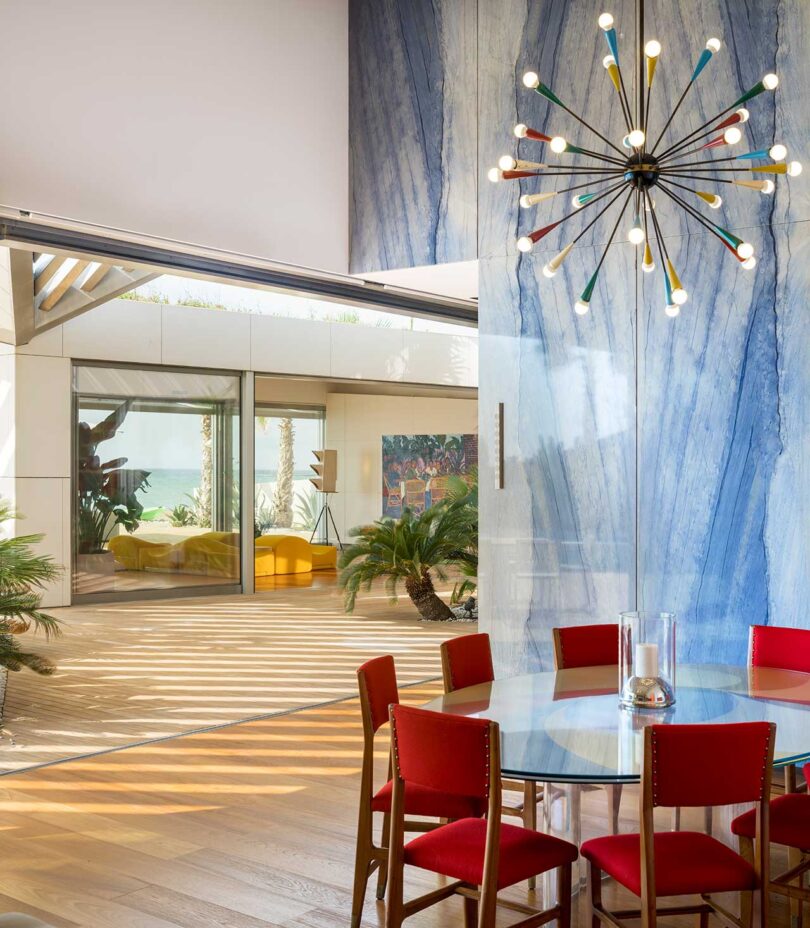 عکس داخلی اتاق غذاخوری مدرن با صندلی های قرمز و دیوارهای مرمر آبی