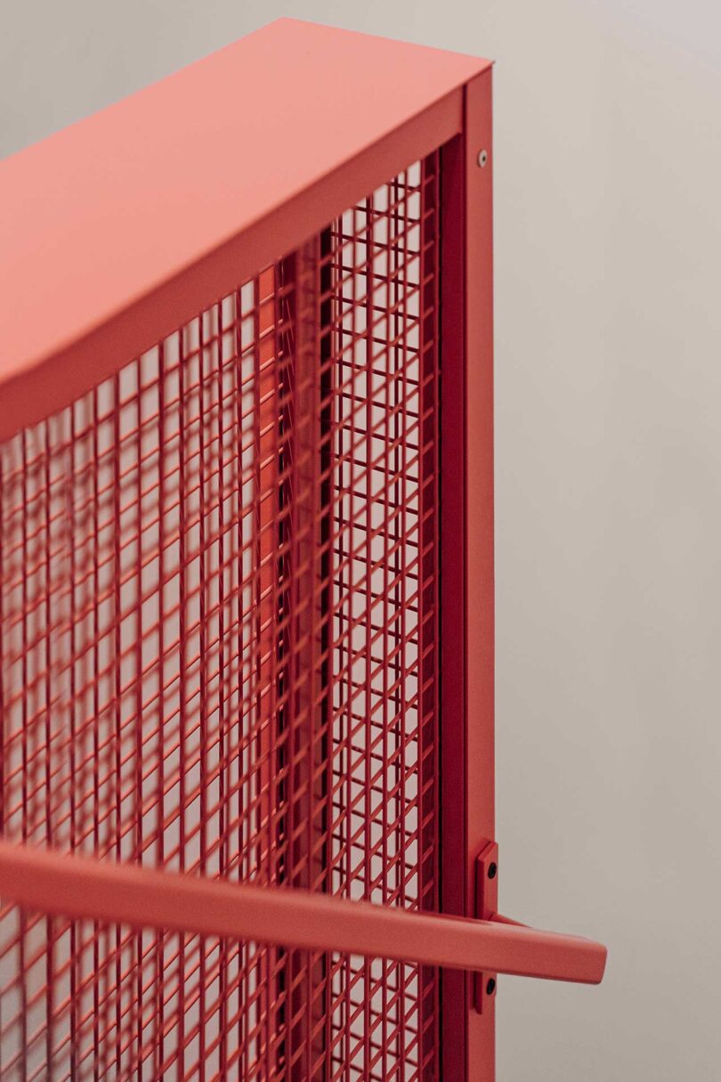 angled down partial view of pink metal perforated structure holding staircase handle